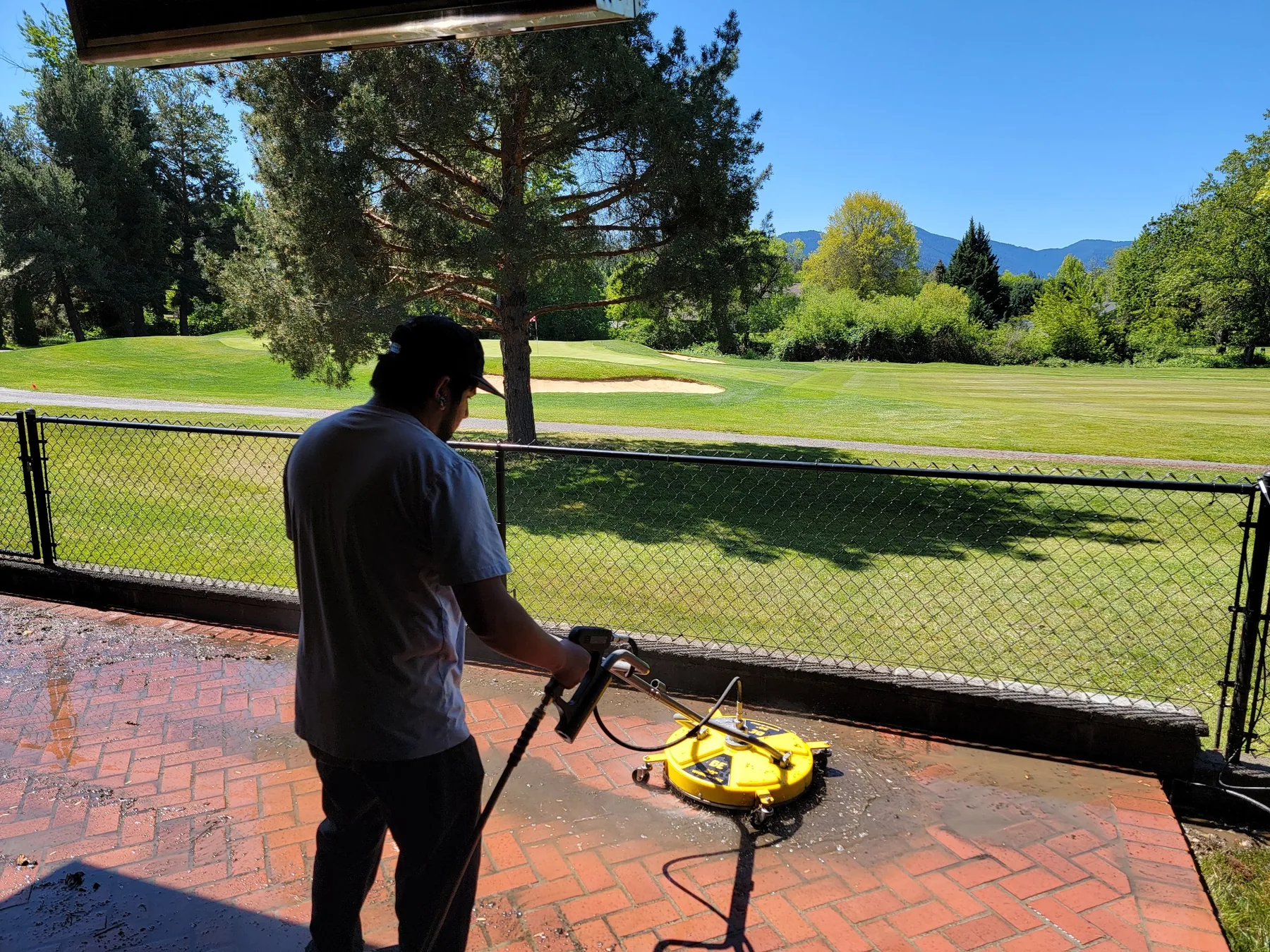 Pressure washing a brick patio overlooking a golf course